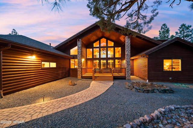 exterior space with covered porch, a shingled roof, and faux log siding