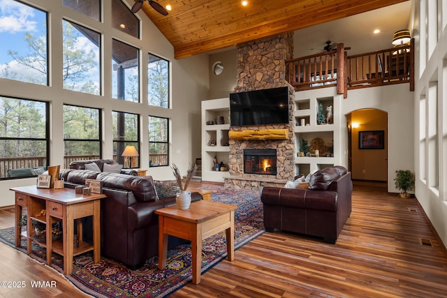 living room with arched walkways, a fireplace, wood finished floors, wood ceiling, and a ceiling fan