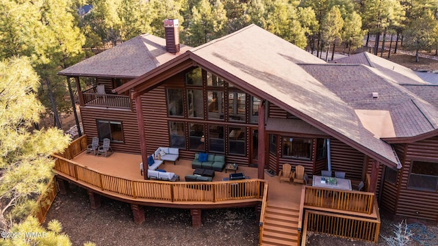 rear view of house with a balcony, a chimney, roof with shingles, a deck, and an outdoor living space