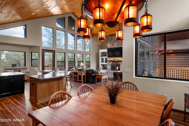 dining room with high vaulted ceiling, wood ceiling, a stone fireplace, and wood finished floors