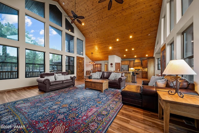 living area with a towering ceiling, wooden ceiling, light wood-style flooring, and ceiling fan