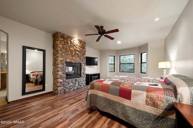 bedroom featuring a ceiling fan, recessed lighting, a stone fireplace, and wood finished floors