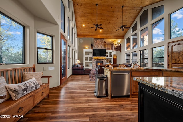 kitchen featuring wood ceiling, a stone fireplace, wood finished floors, high vaulted ceiling, and dishwasher