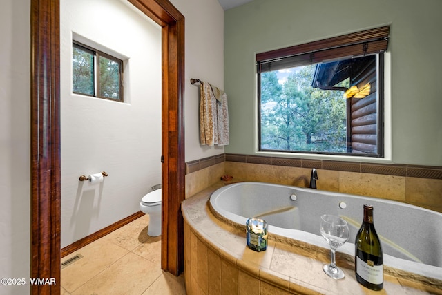 full bathroom with a wealth of natural light, tile patterned flooring, a garden tub, and visible vents