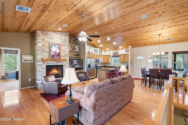 living room with a healthy amount of sunlight, visible vents, a stone fireplace, and light wood finished floors