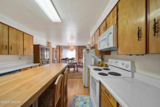 2681 W Reidhead, Show Low, AZ 85901 - kitchen featuring white appliances, brown cabinetry, light wood-type flooring, and a textured ceiling