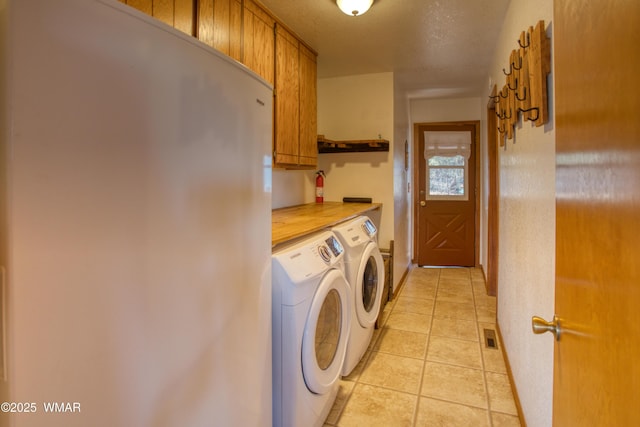 washroom featuring light tile patterned floors, visible vents, a textured ceiling, independent washer and dryer, and cabinet space