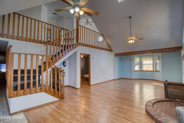 living area featuring stairway, baseboards, a ceiling fan, and wood finished floors