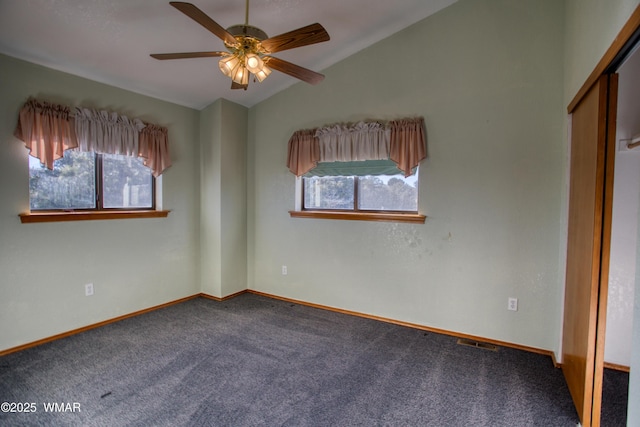 unfurnished bedroom with baseboards, carpet, multiple windows, and vaulted ceiling