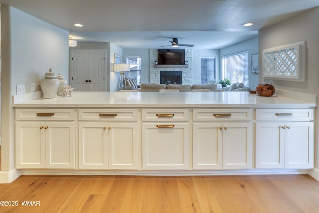 3651 Crown Dancer Dr Unit 8, Pinetop, AZ 85935 - kitchen featuring a stone fireplace, light wood-style flooring, white cabinets, ceiling fan, and recessed lighting