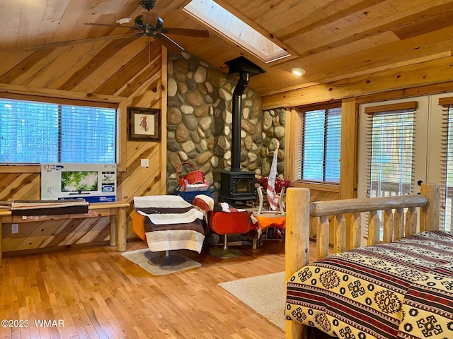 bedroom featuring light wood-type flooring, lofted ceiling with skylight, wood ceiling, and wood walls