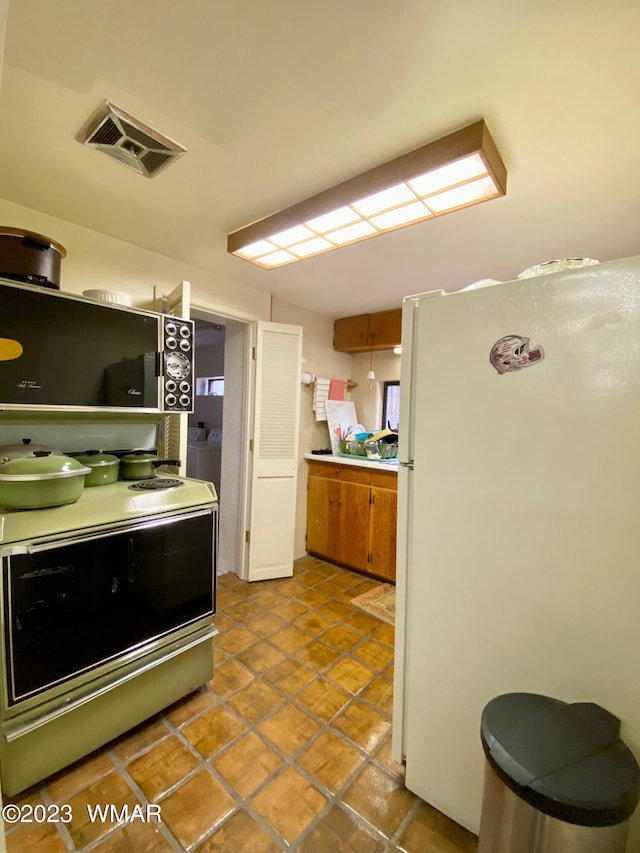 kitchen featuring visible vents, light countertops, range with electric stovetop, and freestanding refrigerator