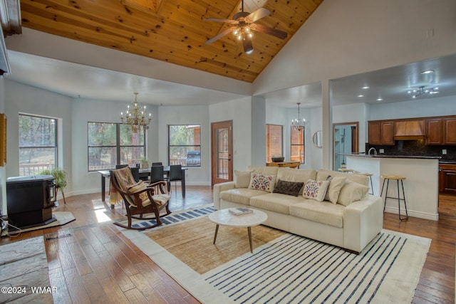 living room featuring baseboards, wooden ceiling, wood finished floors, a wood stove, and high vaulted ceiling