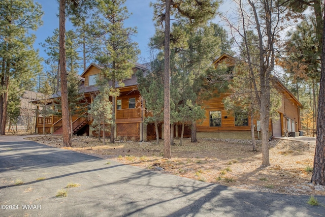 chalet / cabin with a garage, driveway, a porch, and stairway