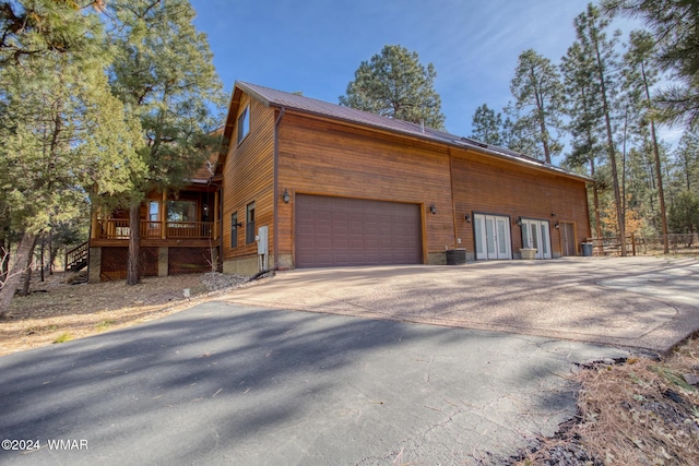 view of side of property featuring a garage, driveway, and stairs