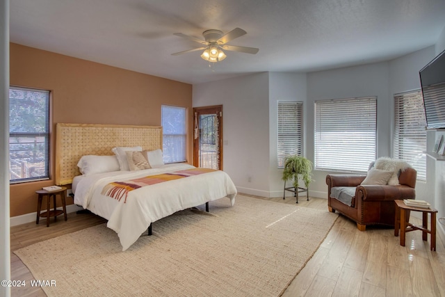 bedroom featuring multiple windows, baseboards, and wood finished floors