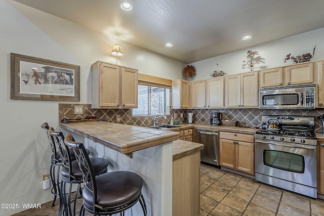 4509 Stone Pine Dr, Pinetop, AZ 85935 - kitchen with stainless steel appliances, a sink, light brown cabinetry, a kitchen breakfast bar, and tile countertops