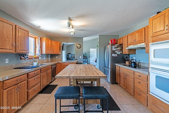 7046 Dusty Saddle Trl, Show Low, AZ 85901 - kitchen with under cabinet range hood, stainless steel appliances, light countertops, a sink, and a textured ceiling