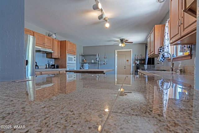 7046 Dusty Saddle Trl, Show Low, AZ 85901 - kitchen with white appliances, under cabinet range hood, a sink, a ceiling fan, and light stone countertops