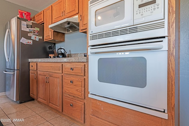 7046 Dusty Saddle Trl, Show Low, AZ 85901 - kitchen with under cabinet range hood, white appliances, light tile patterned floors, light countertops, and brown cabinetry