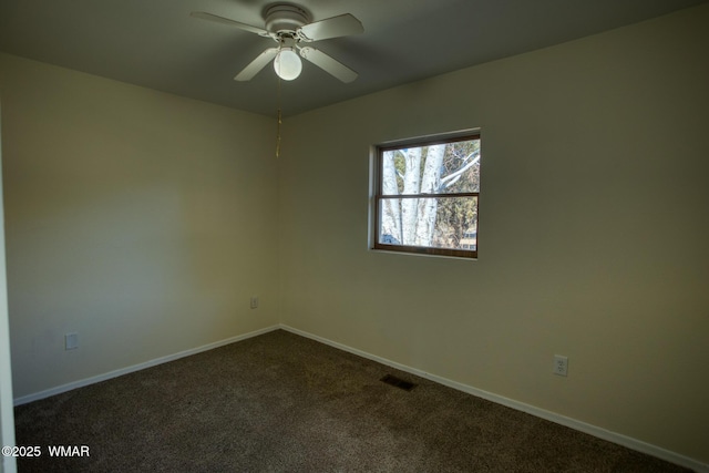 unfurnished room with a ceiling fan, dark carpet, visible vents, and baseboards