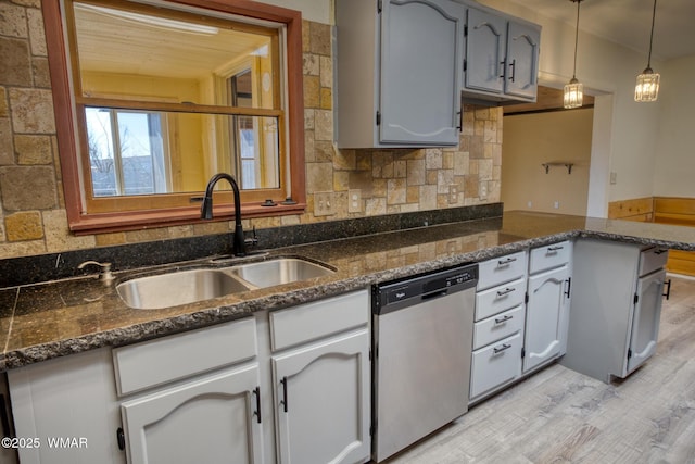 kitchen featuring light wood-style flooring, a sink, stainless steel dishwasher, decorative backsplash, and pendant lighting