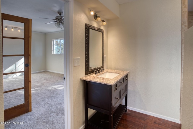 bathroom featuring a ceiling fan, ornamental molding, vanity, wood finished floors, and baseboards