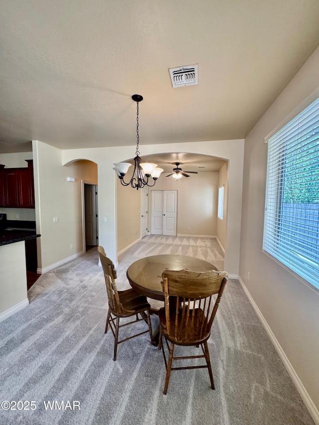 5200 S Morgan Mountain Dr, Show Low, AZ 85901 - dining room featuring arched walkways, light colored carpet, a chandelier, and ceiling fan