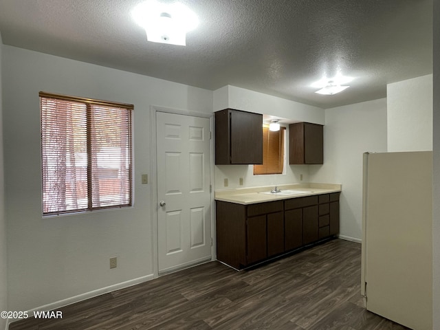 7204 Mark Twain Dr, Pinetop, AZ 85935 - kitchen with dark brown cabinetry, dark wood-type flooring, a sink, baseboards, and light countertops