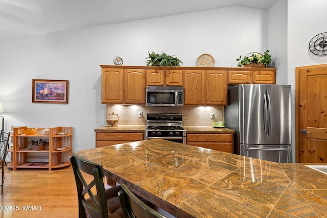 20 W Suncrest Ct, Show Low, AZ 85901 - kitchen with brown cabinetry, a breakfast bar area, tasteful backsplash, vaulted ceiling, and stainless steel appliances