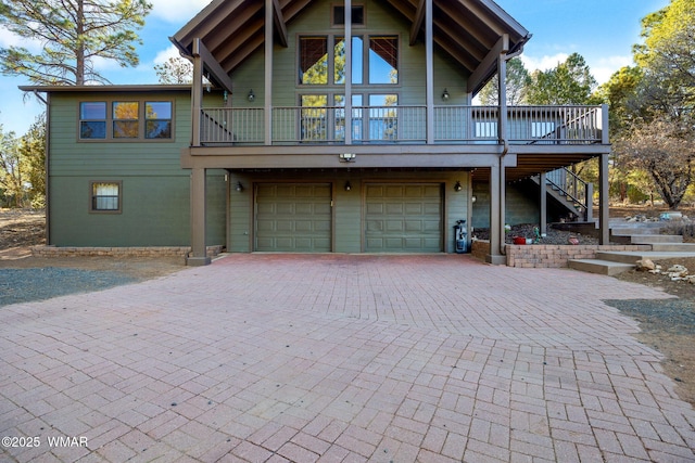 view of front of home with stairs, decorative driveway, and a garage