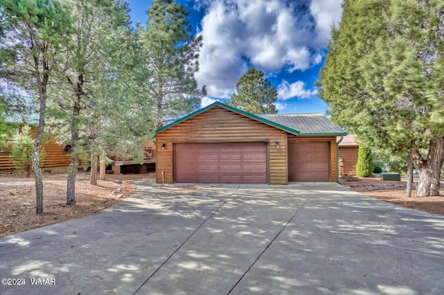 view of front of home with an outbuilding, metal roof, a garage, and faux log siding