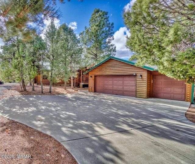 view of front of house with driveway, an attached garage, and faux log siding