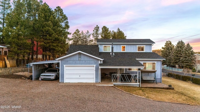 traditional-style house featuring driveway, an attached garage, fence, and roof with shingles