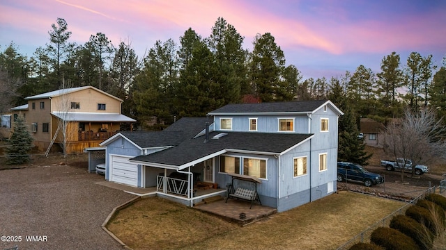 view of front of house with driveway, a shingled roof, and fence