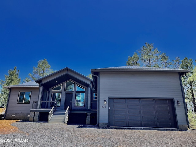 view of front of house featuring metal roof, crawl space, and gravel driveway