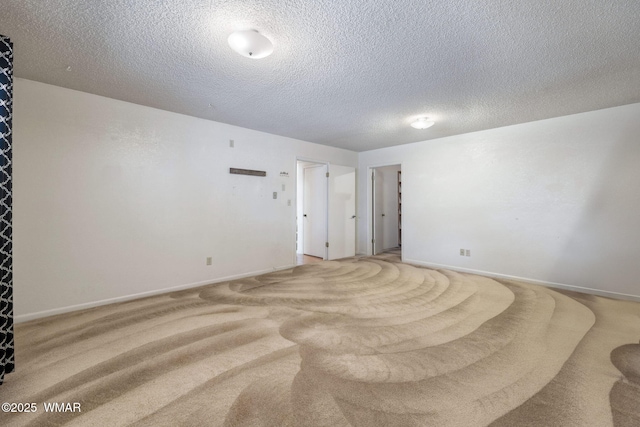 carpeted spare room featuring a textured ceiling and baseboards