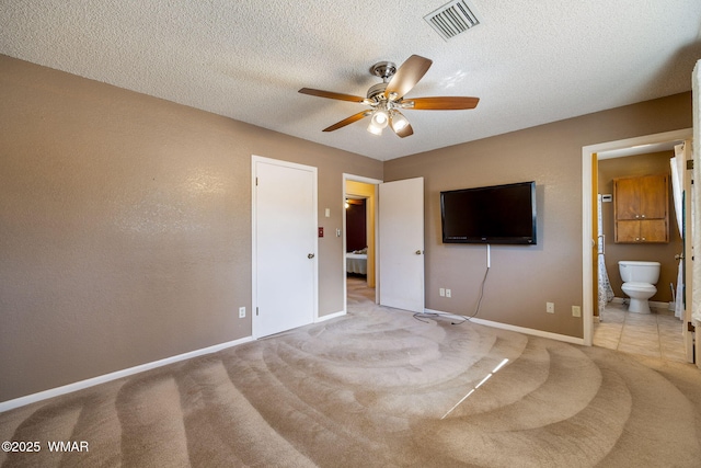 unfurnished bedroom with light carpet, visible vents, a textured ceiling, and ensuite bath