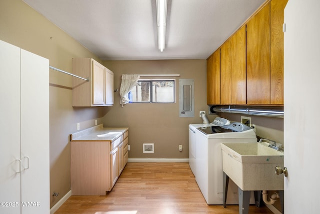 clothes washing area with light wood finished floors, independent washer and dryer, cabinet space, and baseboards