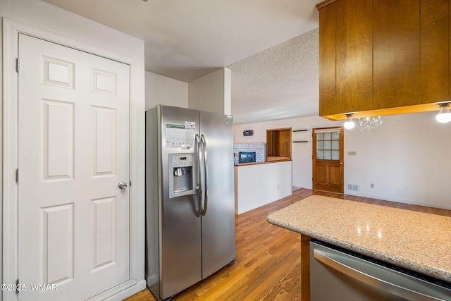 kitchen with visible vents, appliances with stainless steel finishes, a textured ceiling, light stone countertops, and light wood-type flooring