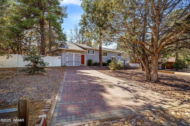 ranch-style house featuring a garage, decorative driveway, and fence