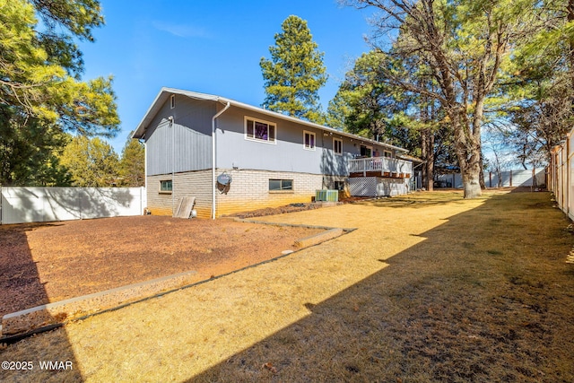 rear view of property featuring a fenced backyard, central AC unit, and a yard