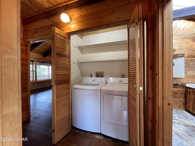 clothes washing area featuring wooden ceiling, laundry area, wood walls, and washing machine and clothes dryer