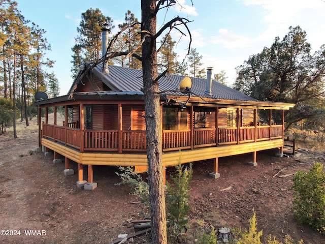 rear view of property featuring metal roof and a wooden deck