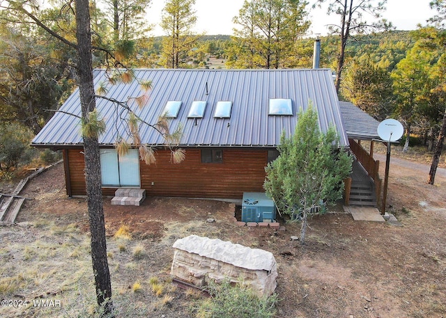 view of side of property featuring entry steps, metal roof, and central air condition unit