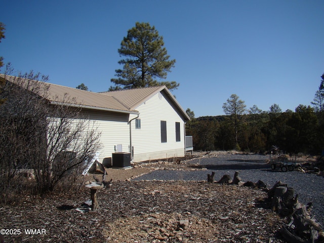 view of property exterior with central AC and metal roof