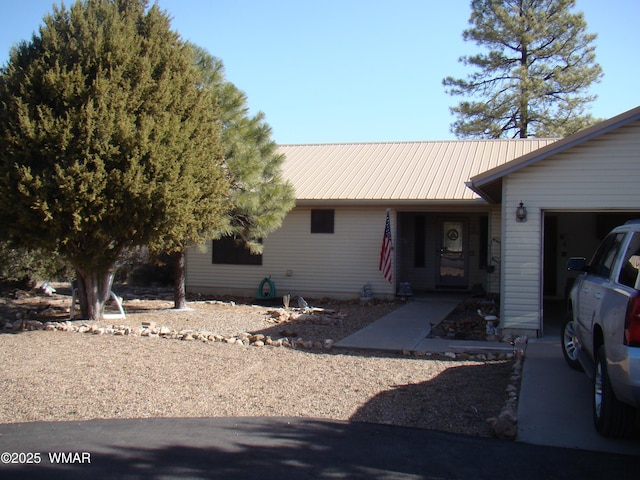 ranch-style home featuring an attached garage and metal roof