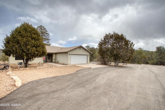 ranch-style home with an attached garage, driveway, and metal roof