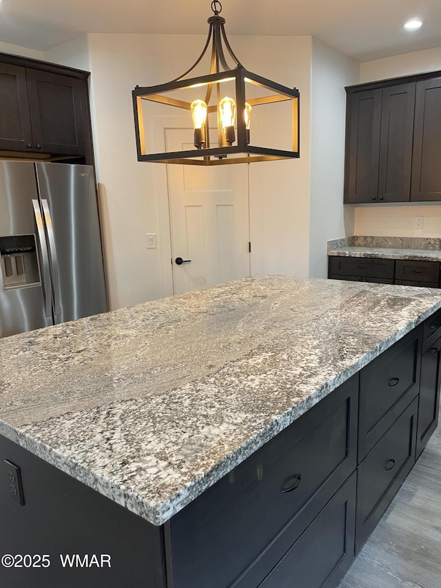 2490 Aspen Run, Pinetop, AZ 85935 - kitchen featuring light stone countertops, stainless steel fridge, a center island, light wood-type flooring, and an inviting chandelier