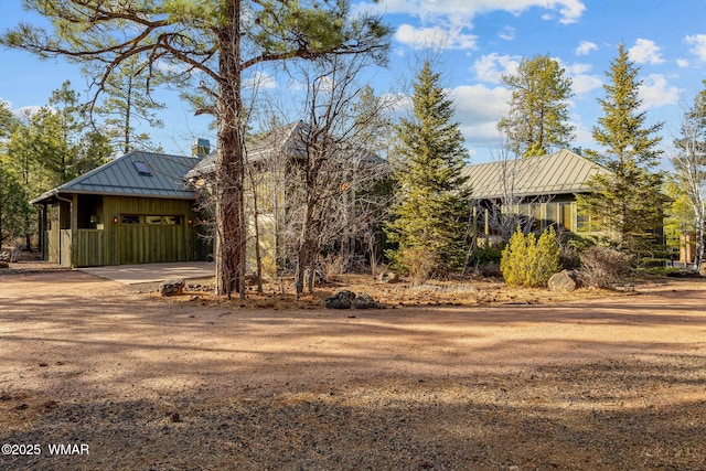 exterior space featuring a standing seam roof, dirt driveway, and metal roof